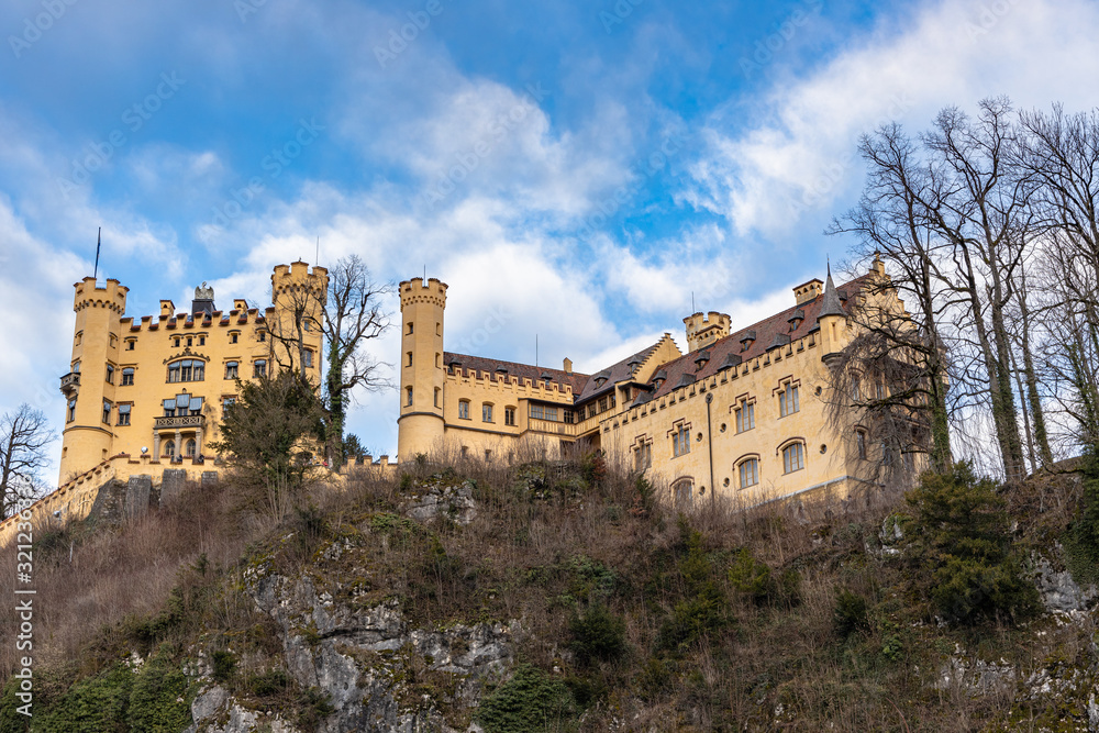 Beautiful view of the famous Hohenschwangau Castle on a sunny day in winter, with blue sky and cloud background, Schwangau, Bavaria, Germany