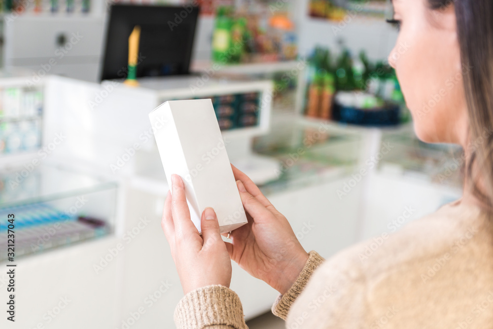closeup female hands holding a white box in a store or pharmacy approaching the cashbox while investigating the label closeup female hands holding a white box in a store or pharmacy approaching the cashbox while investigating the label