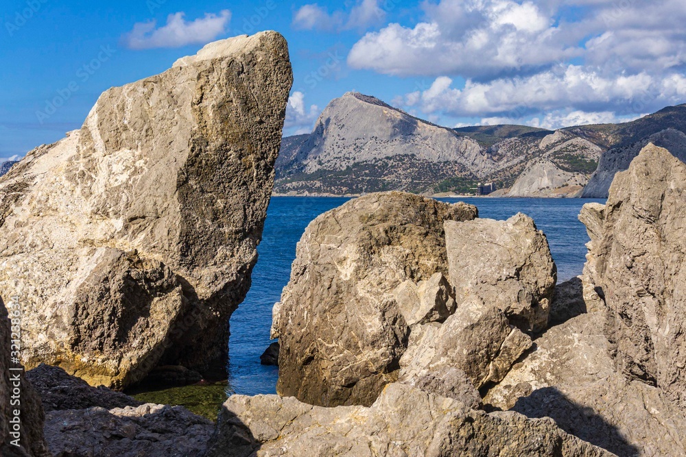 Rocky coast of Black Sea. Cape Alchak. Wildlife near ancient city built by Genoese. Velvet season in Sudak in Crimea. Huge stones and boulders in sea and on background of sea. Close-up.