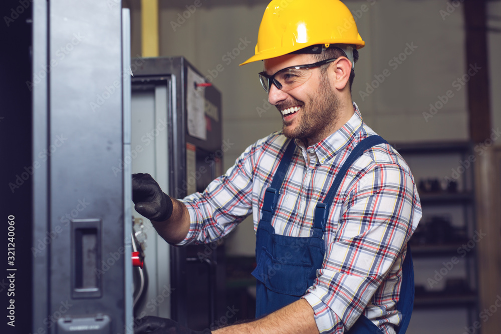 Industry Worker entering data in CNC machine at factory. Industry Worker entering data in CNC machine at factory.