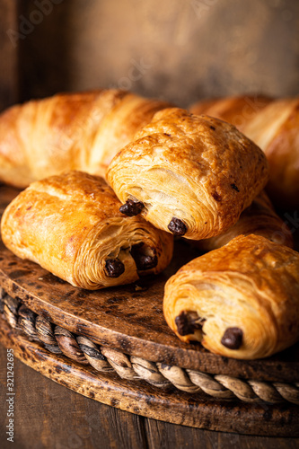 Photography Coffee break with freshly baked sweet buns puff pastry with chocolate and croissants on old wooden background