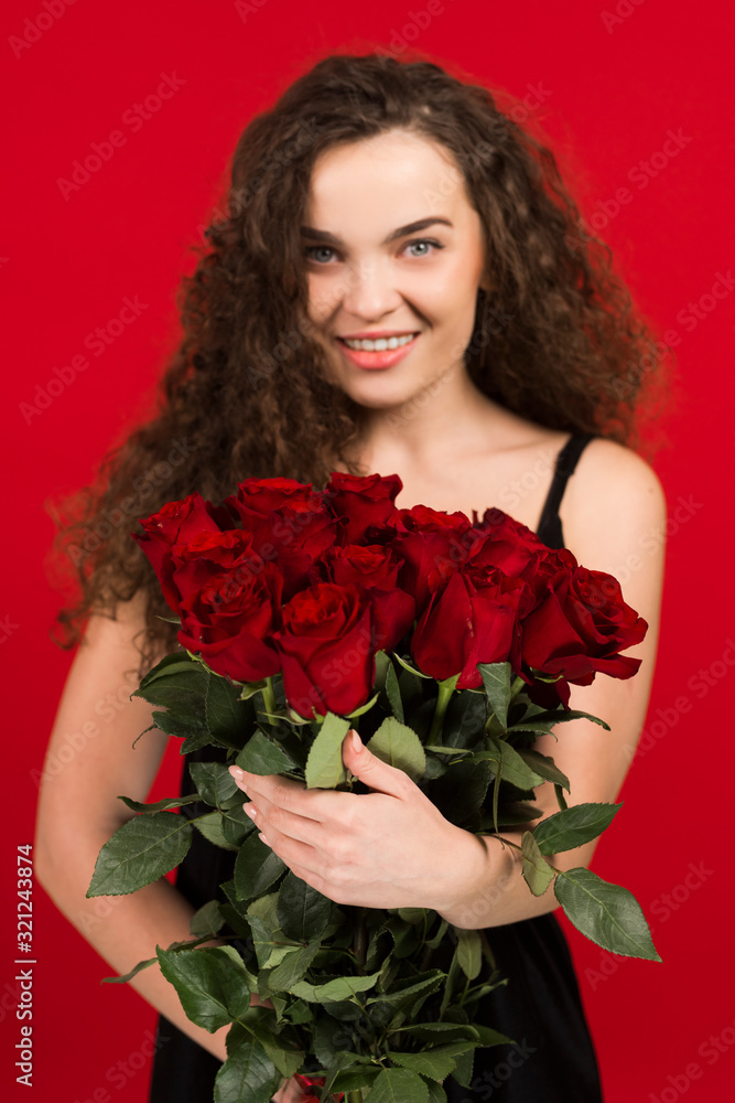 Happy young woman holding flowers isolated on red background Happy young woman holding flowers isolated on red background