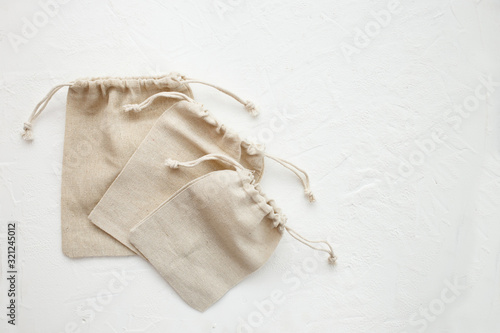 Canvas bags with drawstring, mockup of small eco sack made from natural cotton fabric cloth flat lay on white background. Flat lay, top view.