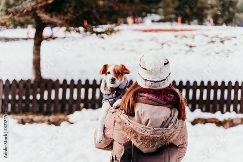 woman holding on shoulder her cute jack russell dog. Winter season at the mountain