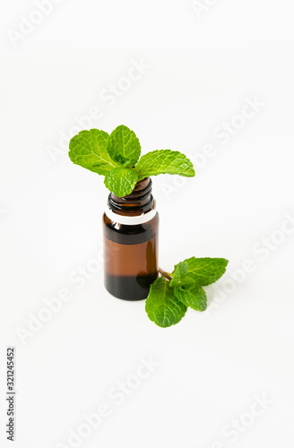 isolated glass bottle with aromatic oil and a sprig of mint on a white background