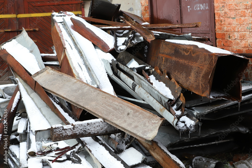 Snow-covered piles of rusty iron scrap / Piles of sheets of rusty iron prepared for recycling, disposal Snow-covered piles of rusty iron scrap / Piles of sheets of rusty iron prepared for recycling, disposal