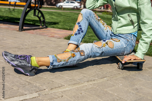 Street fashion, young woman in torn jeans with decor, copy space 