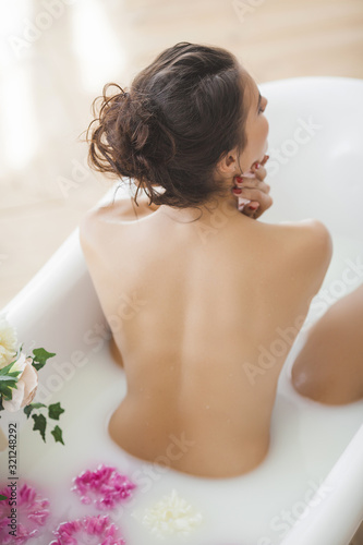 Fotografering Perfect woman bathing with flowers and milk