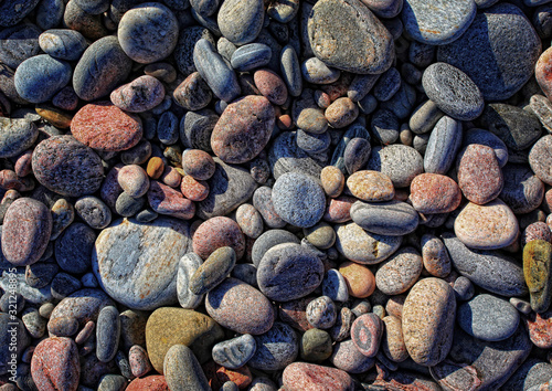 Bunte, runde, abgeschliffene Steine liegen am Strand in der Sonne