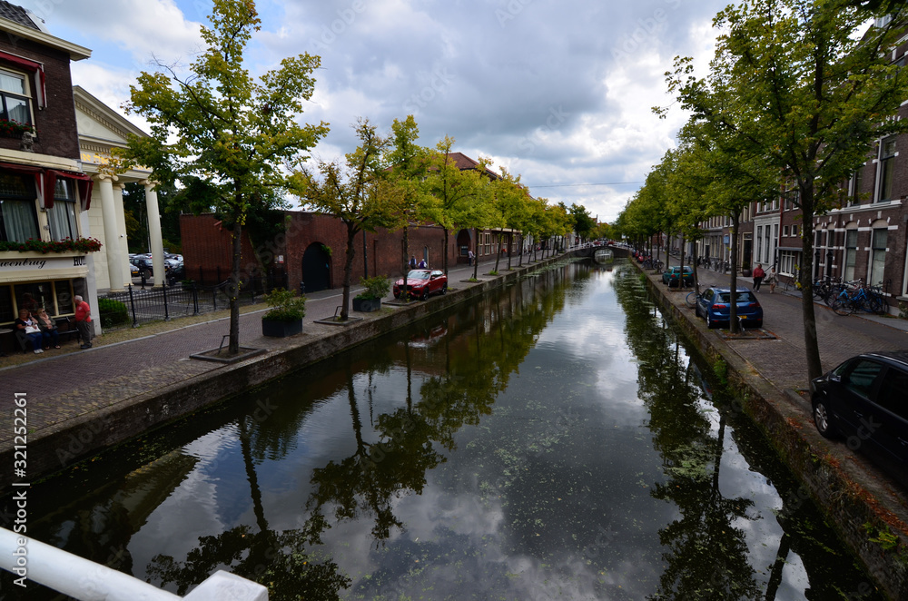 Delft, the netherlands, august 2019. The pretty and romantic canals, smaller than in Amsterdam. The aquatic plants create a green carpet, the bridges frame the flower boxes in warm and bright colors.