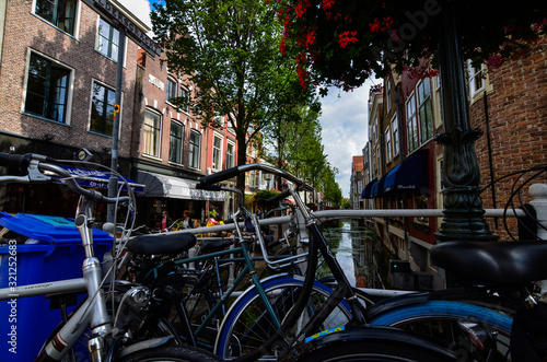 Delft, the netherlands, august 2019. The pretty and romantic canals. The aquatic plants create a green carpet, the bridges frame the flower boxes in warm and bright colors. Parked bikes.