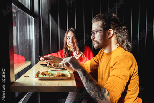 Young couple enjoying the tasty fast food in restaurant