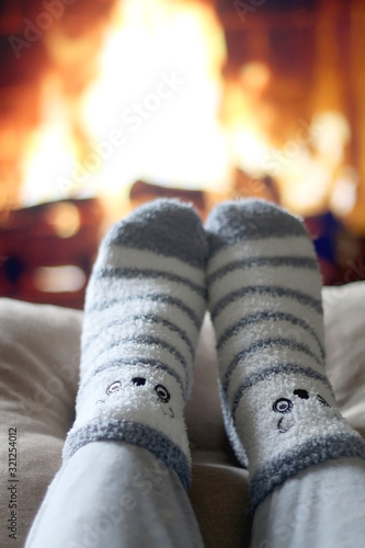 Feet in cute fuzzy socks in front of a fireplace. Selective focus.