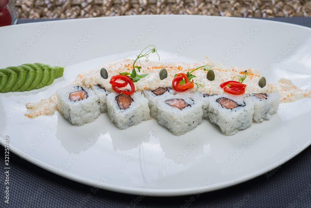 Traditional rolls with fish and rice on a white plate with sauce and wasabi. Japanese food. Traditional rolls with fish and rice on a white plate with sauce and wasabi. Japanese food.