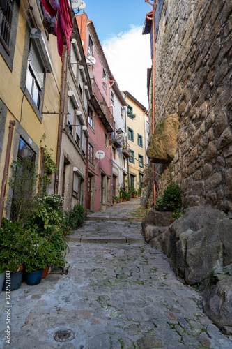 Narrow cobblestone alley in Porto, Portugal with potted plants and cute doorways
