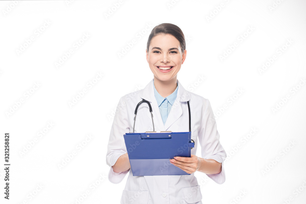 Beautiful doctor smiling at camera while writing on clipboard isolated on white Beautiful doctor smiling at camera while writing on clipboard isolated on white