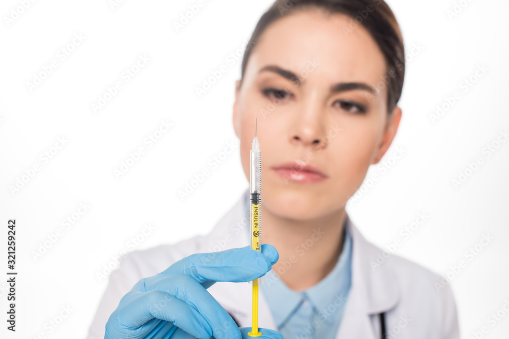 Selective focus of attractive doctor looking at syringe with vaccine isolated on white Selective focus of attractive doctor looking at syringe with vaccine isolated on white