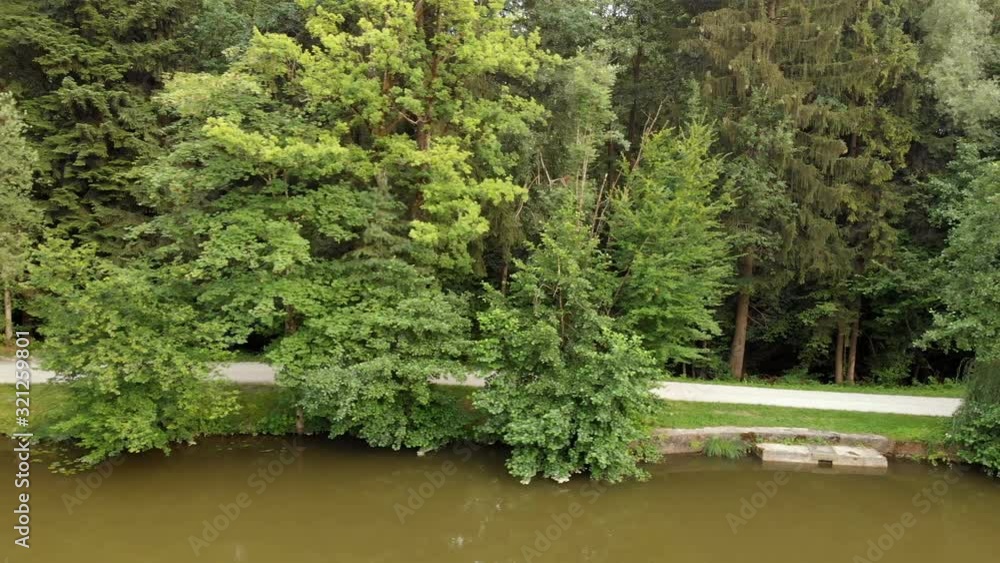 A sportsman is riding his bicycle around a lake on a gorgeous day. Aerial shot. A sportsman is riding his bicycle around a lake on a gorgeous day. Aerial shot.