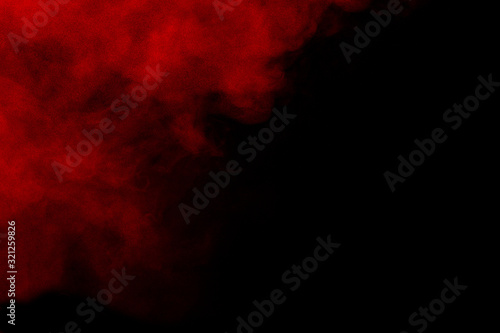 Red color powder explosion on black background.Freeze motion of red dust particles splashing. © Pattadis