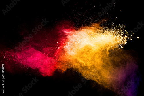Red yellow powder explosion cloud on black background. Freeze motion of red yellow color dust particles splashing.