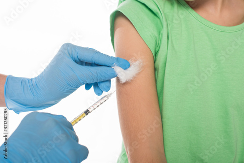 Cropped view of pediatrician holding cotton wool and syringe while doing vaccine injection to kid isolated on white