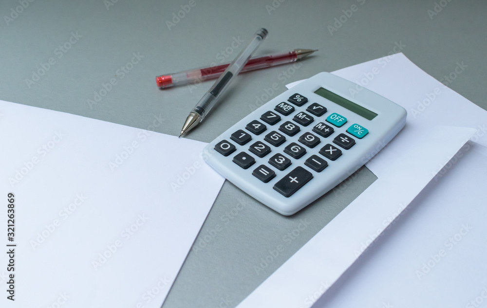 Empty letter and envelope with a calculator and pens and euro coins on a modern blue background Empty letter and envelope with a calculator and pens and euro coins on a modern blue background