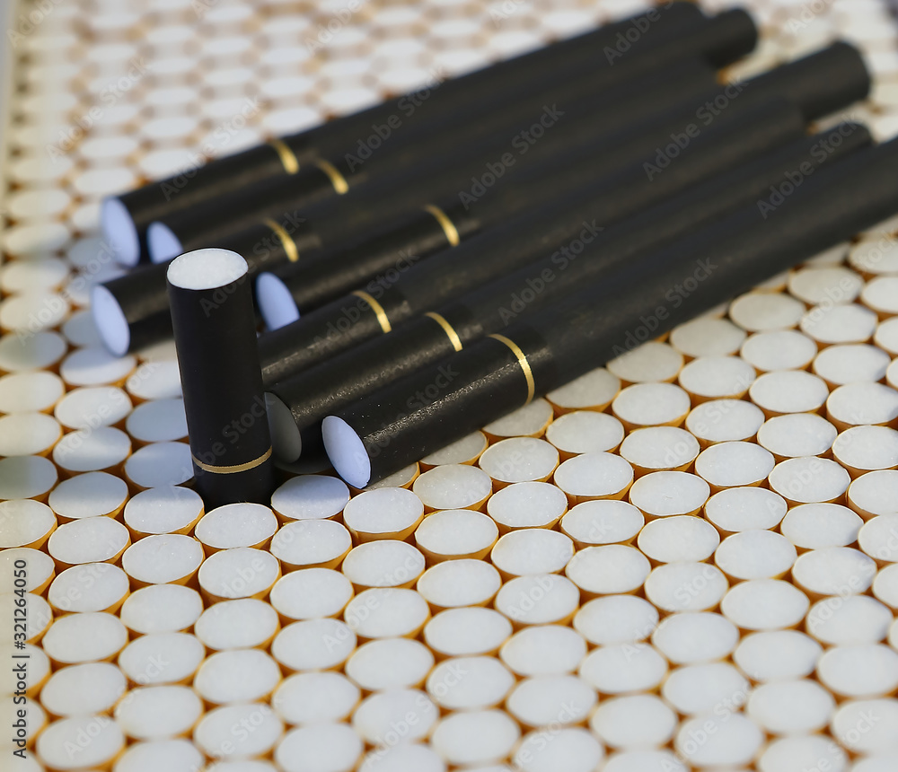 Naklejka premium Cigarette filters Blank cigarette paper top view Several white and black cigarettes (tubes) with yellow and black filters