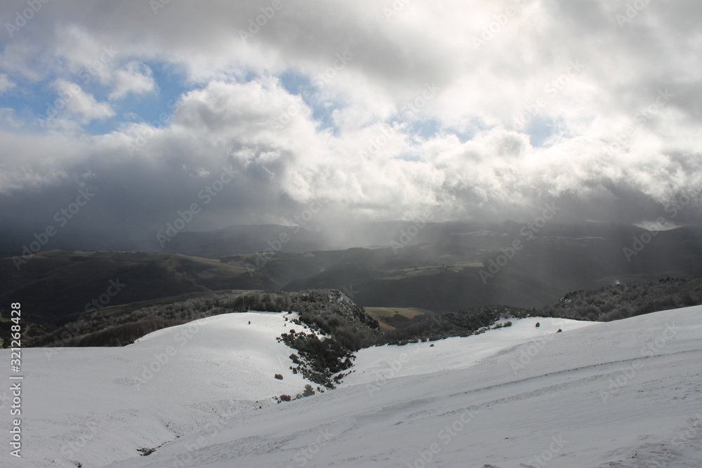 Snowy hillside with sun rising and clouds