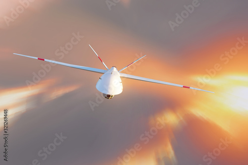 Unmanned military drone patrols high in the sky at sunset. The view is straight ahead.