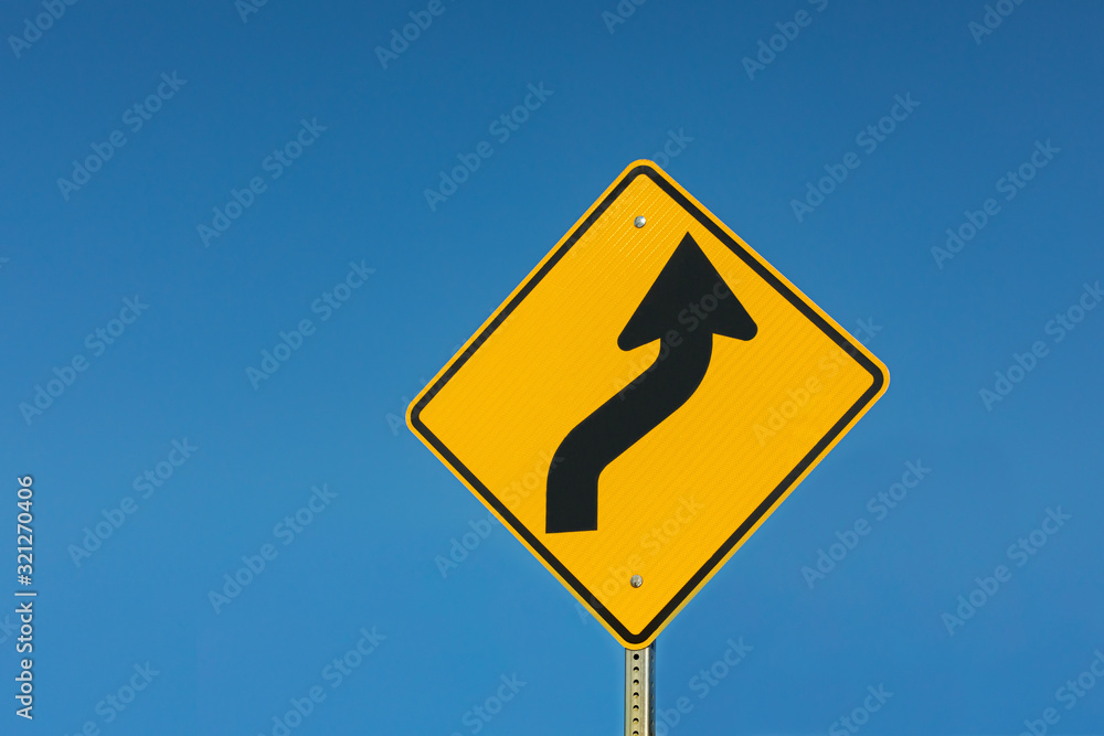 yellow reflective winding road ahead traffic sign isolated on sunny blue sky background yellow reflective winding road ahead traffic sign isolated on sunny blue sky background