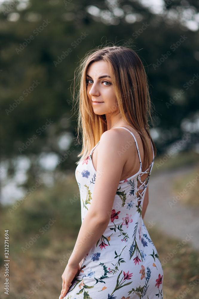 Portrait of young attractive chestnut beautiful woman on green forest background in fresh summer dress Portrait of young attractive chestnut beautiful woman on green forest background in fresh summer dress