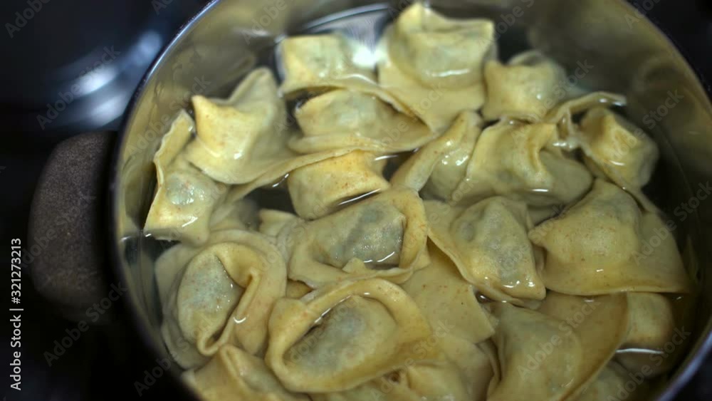 Overhead, closeup shot of tortellini ravioli filled pasta boiling in a pot full of boiling water. Soft focus.