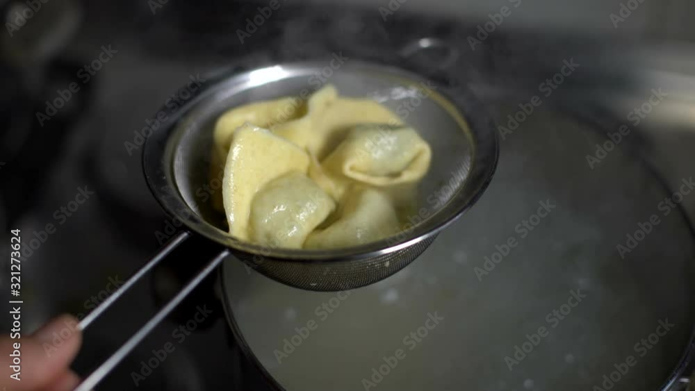 Woman draining tortellini ravioli filled pasta with a colander. Preparing food. Woman draining tortellini ravioli filled pasta with a colander. Preparing food.