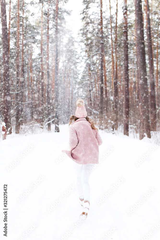 A beautiful pretty young girl with curly hair and a snow-white smile in a pink fur coat is walking and fooling around in the winter forest against the background of snow and trees, enjoy A beautiful pretty young girl with curly hair and a snow-white smile in a pink fur coat is walking and fooling around in the winter forest against the background of snow and trees, enjoy