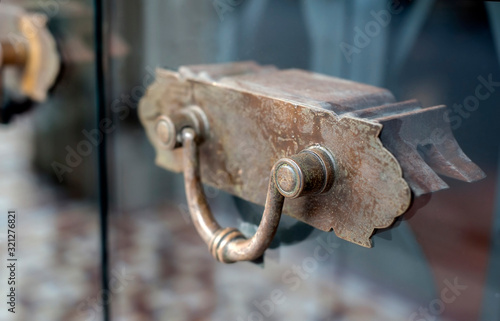 Penang, Malaysia - January 21, 2020 : Vintage Bronze door handle on main entrance frameless glass door in one of the shop house historic colonial district of Georgetown.