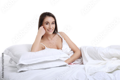 Pretty young beautiful girl woke up and sitting on a bed
