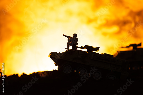 Silhouette of toy soldier on tank with fire at background, battle scene