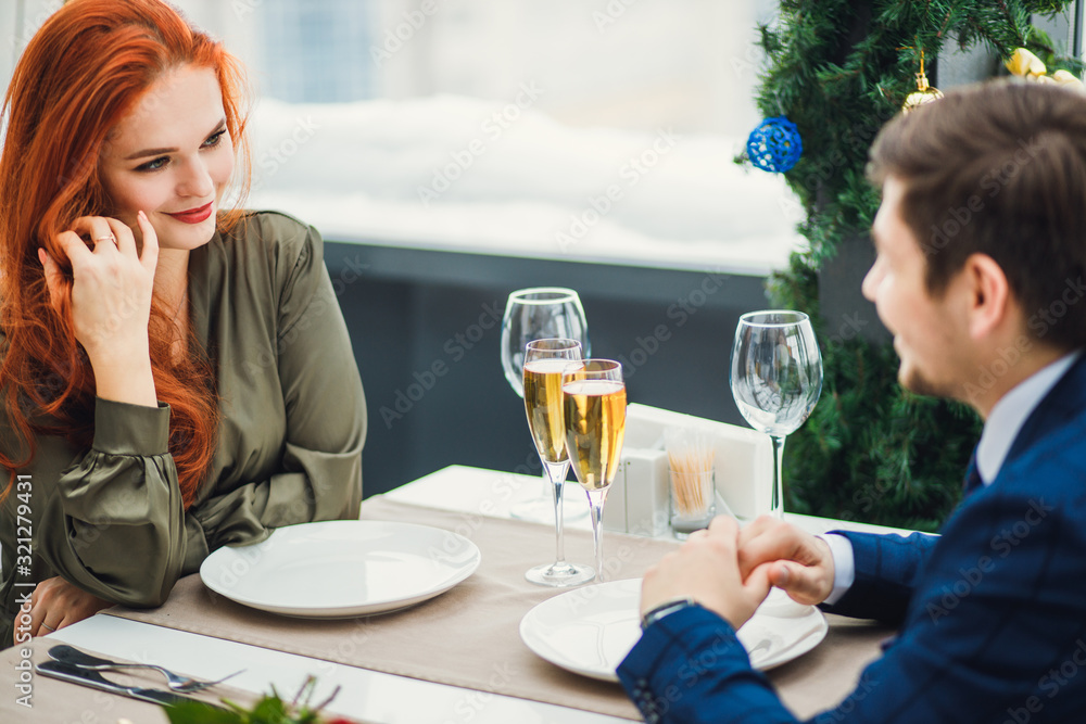 cute caucasian beautiful lady in dress sit with man in restaurant, wearing dress. man in tuxedo nicely talk with redhaired female. romantic, celebration, date, love concept cute caucasian beautiful lady in dress sit with man in restaurant, wearing dress. man in tuxedo nicely talk with redhaired female. romantic, celebration, date, love concept