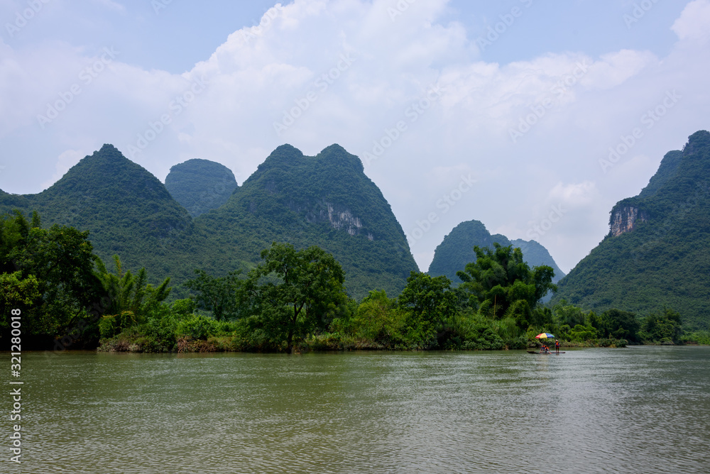 Tourists bamboo rafting along the Yulong river with beautiful karst mountains landscape in the background in Yangshuo County