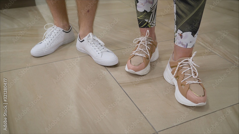 Man in white sneakers on asphalt at sunset. Men's shoes. Women's and men's sports shoes. The guy and the girl in sports shoes. A new collection of men's and women's sports shoes Man in white sneakers on asphalt at sunset. Men's shoes. Women's and men's sports shoes. The guy and the girl in sports shoes. A new collection of men's and women's sports shoes