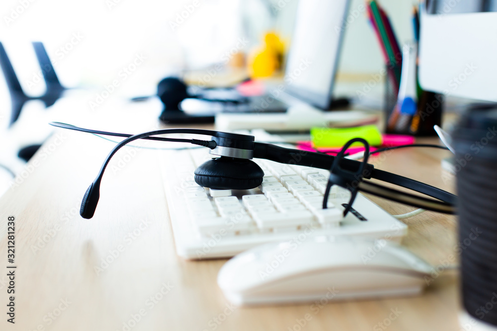 Closeup of headphone on computer keyboard at call center service office space. Customer service tools concept. Closeup of headphone on computer keyboard at call center service office space. Customer service tools concept.