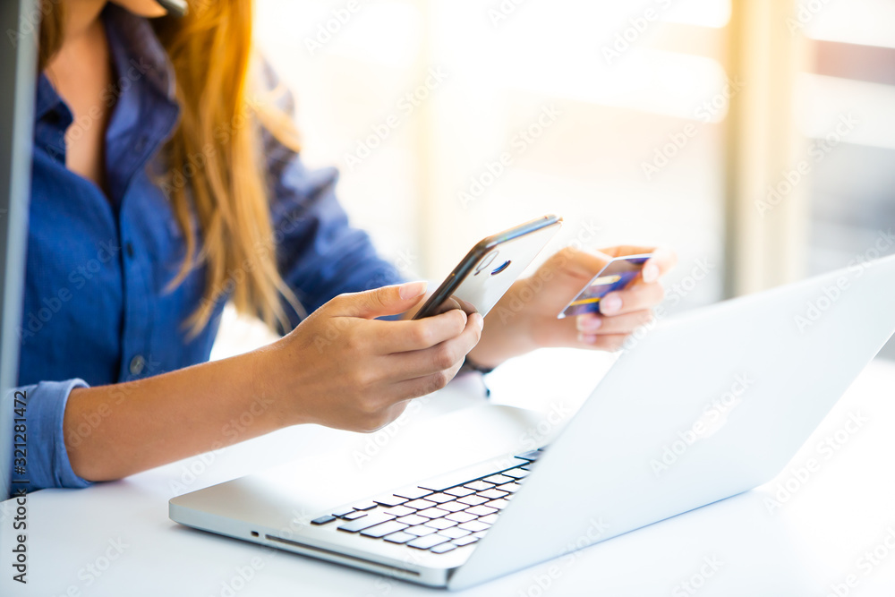 online shopping concepts. Woman hand holding mobile phone and credit card with Payment Detail page display. using smartphone and laptop computer for online shopping online shopping concepts. Woman hand holding mobile phone and credit card with Payment Detail page display. using smartphone and laptop computer for online shopping