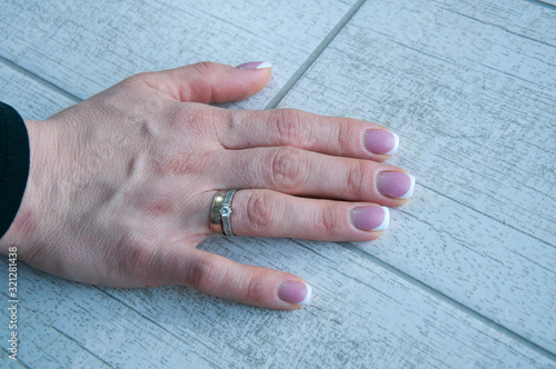 Woman's hand with pink manicure and a ring.
