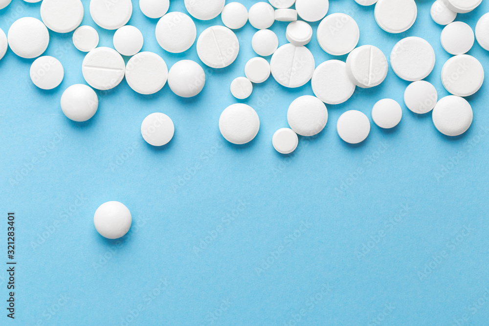 scattered white pills on a blue table. Layout for special offers such as advertising or other ideas. The concept of medicine, pharmacy and healthcare. Space for copy. flat lay for text or logo. scattered white pills on a blue table. Layout for special offers such as advertising or other ideas. The concept of medicine, pharmacy and healthcare. Space for copy. flat lay for text or logo.