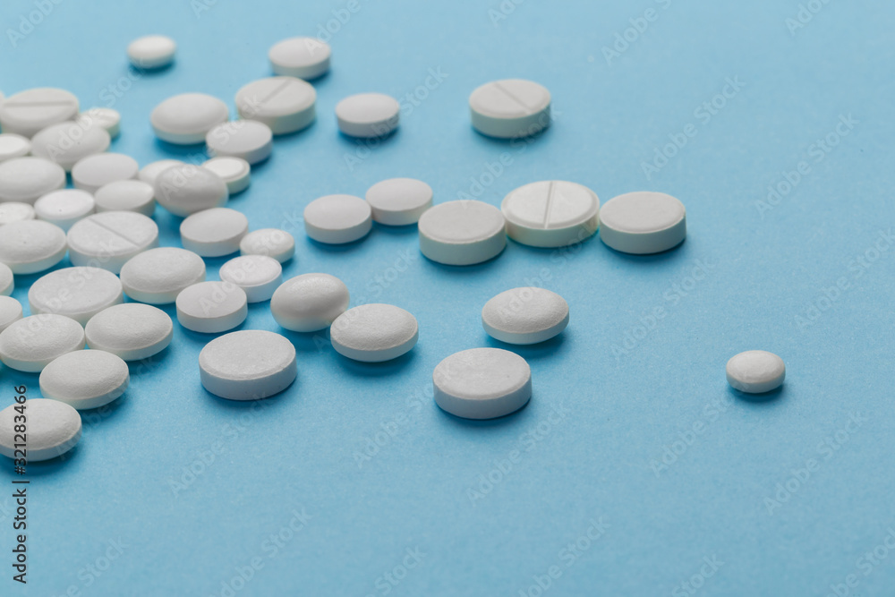 scattered white pills on a blue table. Layout for special offers such as advertising or other ideas. The concept of medicine, pharmacy and healthcare. Space for copy. flat lay for text or logo. scattered white pills on a blue table. Layout for special offers such as advertising or other ideas. The concept of medicine, pharmacy and healthcare. Space for copy. flat lay for text or logo.
