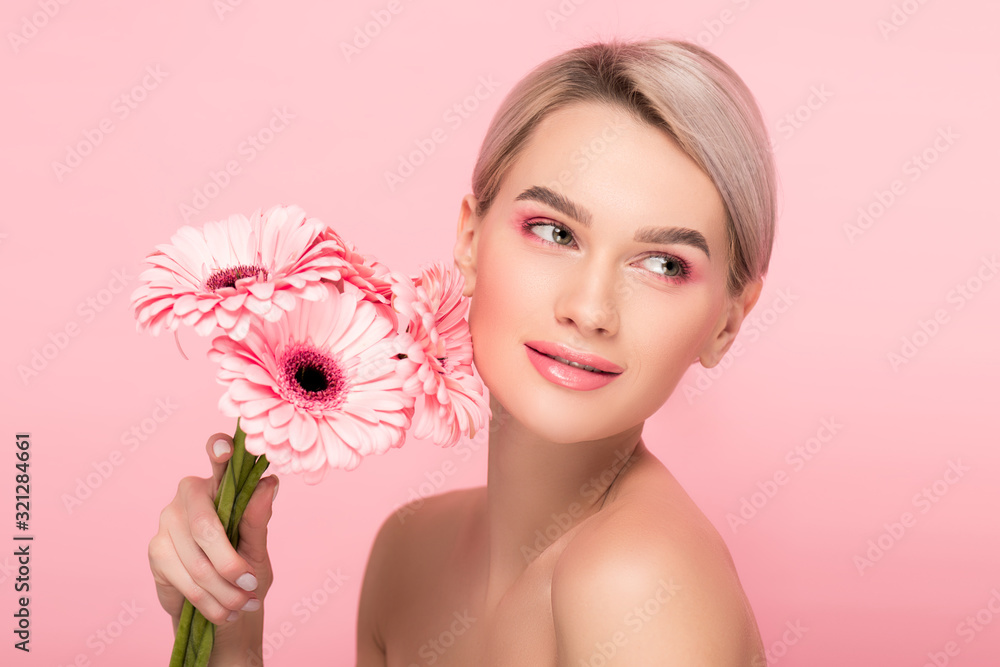 beautiful girl holding pink gerbera flowers, isolated on pink