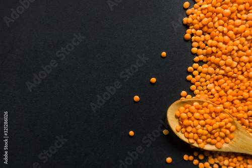 Red lentils with a spoon on black background