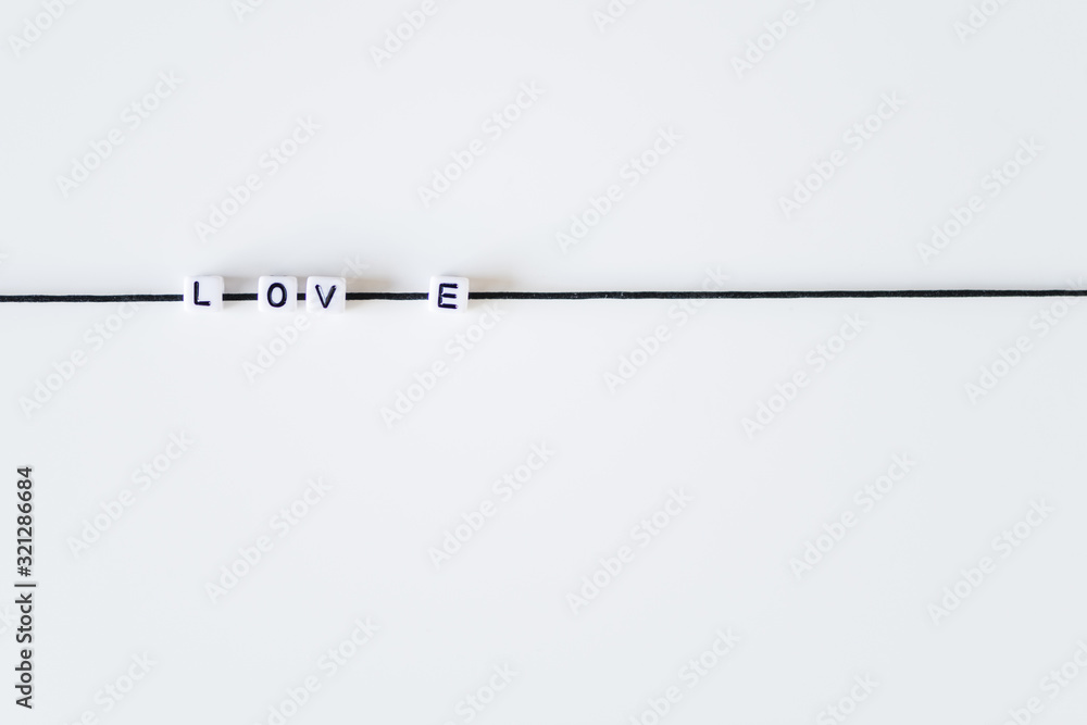 Love word made from letters printing blocks on a black rope. White background Love word made from letters printing blocks on a black rope. White background