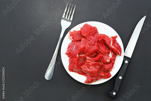 Raw red meat on black background.