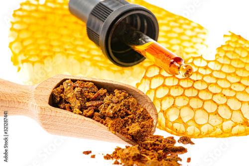 propolis tincture and a wooden spoon of propolis granules photo